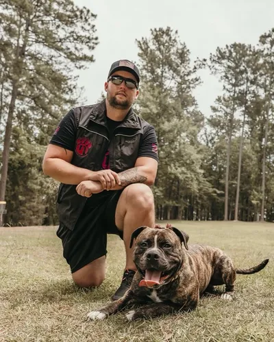 Zack Barkley kneeling beside a brindle bulldog